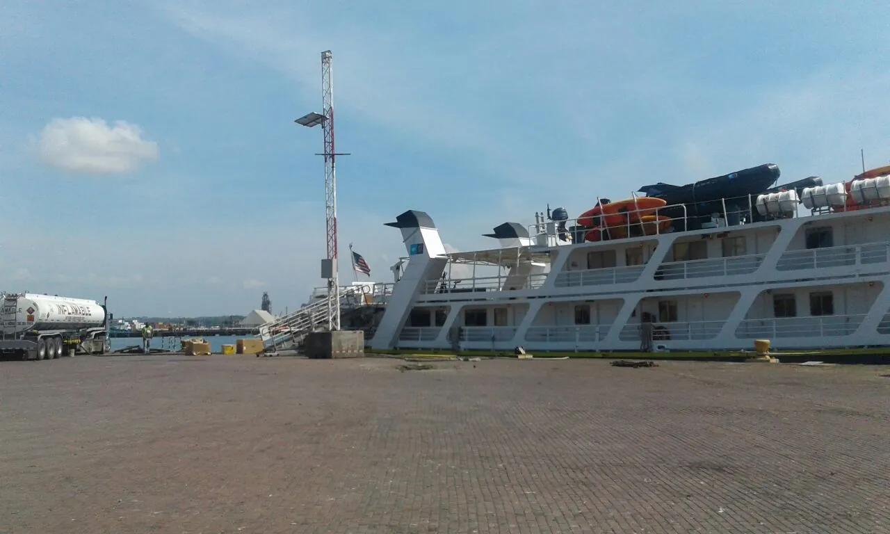 Barco de pasajeros atracado en el muelle, con un camión cisterna estacionado al fondo