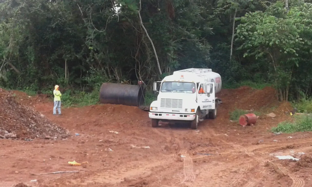 Camión cisterna de PetroSolutions en un terreno de tierra roja, con un trabajador con ropa reflectiva y un tanque metálico al fondo