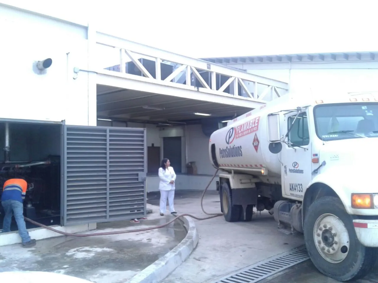 Camión cisterna de PetroSolutions abasteciendo con manguera el cuarto de generador de un edificio